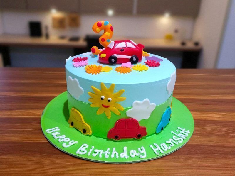 Colorful Car Theme Cake 3 Colorful Car Theme Cake with cute fondant cars, sun, clouds, and flowers, handcrafted by LallanTop Cake Shop for kids’ birthday celebrations in Noida, East Delhi, Indirapuram, Vaishali, Vasundhra, and nearby areas.